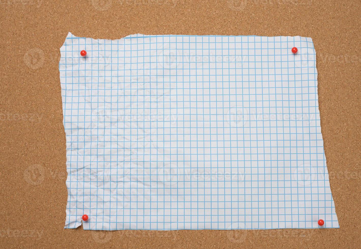 blank torn crumpled white squared sheet of paper pinned to brown cork board photo
