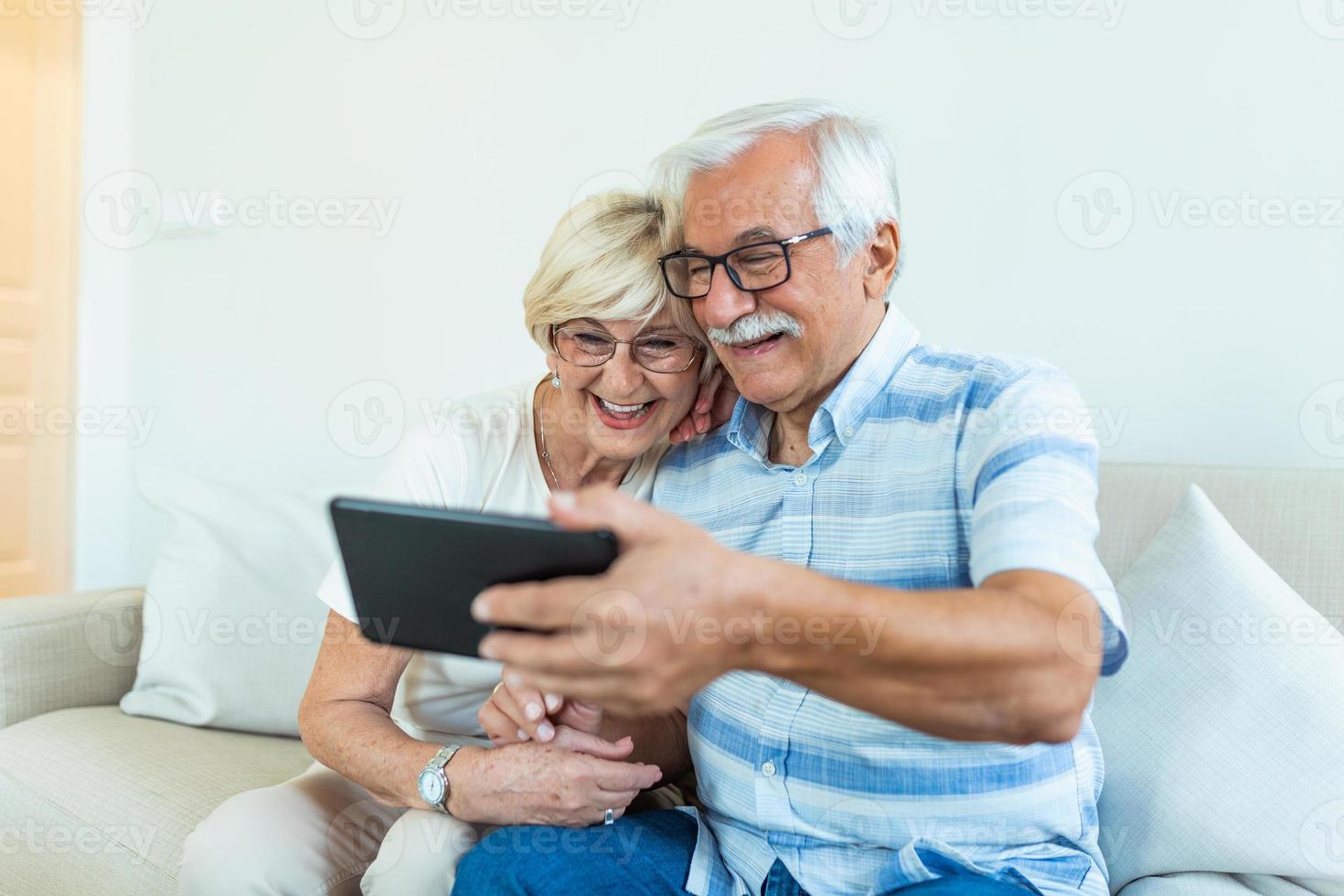 personas mayores alegres navegando en Internet con tableta, familia, tecnología, edad y concepto de personas - feliz pareja mayor con computadora de tableta en casa foto