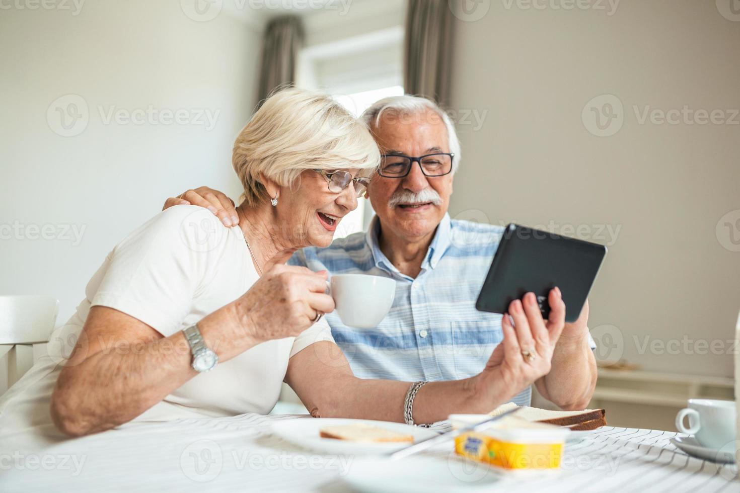 Senior man and his wife are using a digital tablet and communicating with their kids. Happy senior couple is having breakfast and having an online conversation with their family and sending greetings. photo
