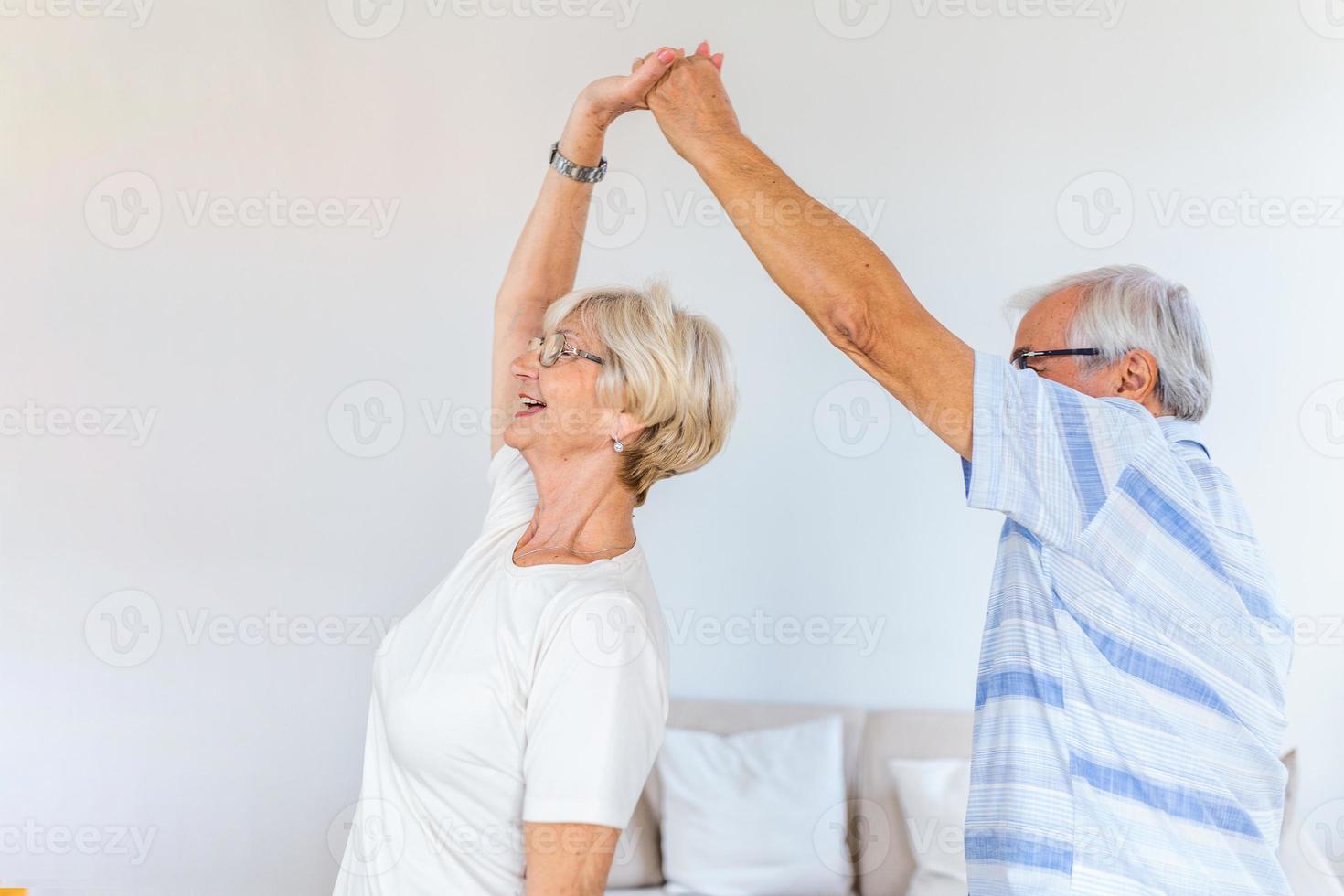 Carefree happy active old senior couple dancing jumping laughing in living room, cheerful retired elder husband holding hand of mature middle aged wife enjoy fun leisure retirement lifestyle at home 19607763 Stock photo