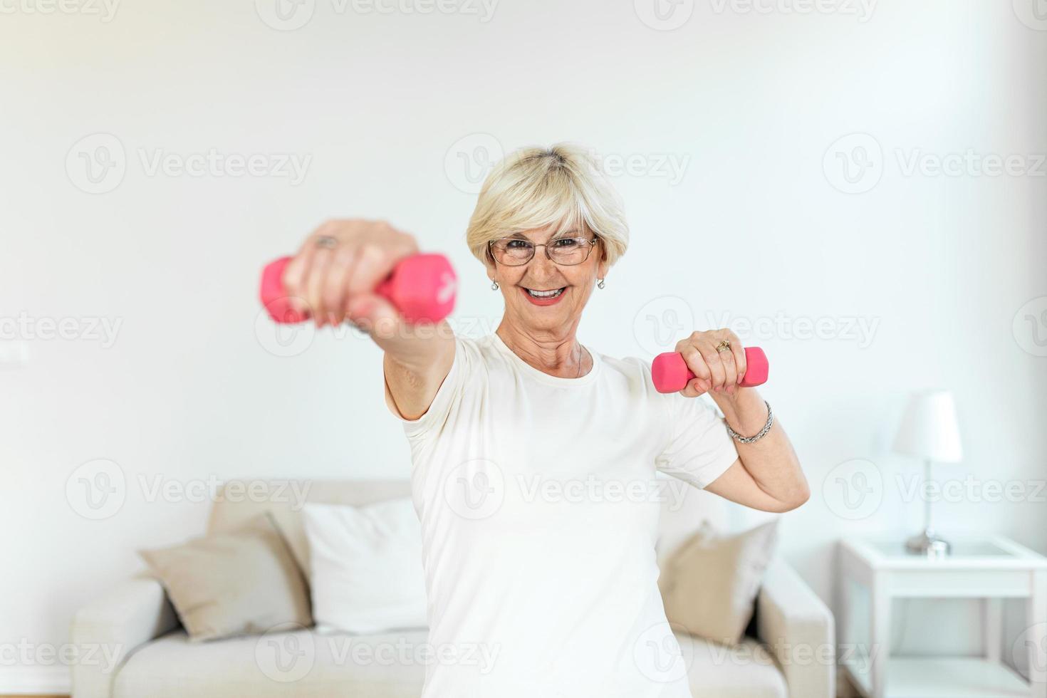 Senior woman exercise with dumbbells at home . happy mature woman doing arm workout using dumbbells. Elderly woman prefers healthy lifestyle photo