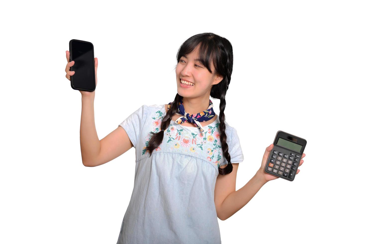 Portrait of beautiful young asian woman in denim dress holding calculator and smartphone on white background. business shopping online concept. photo