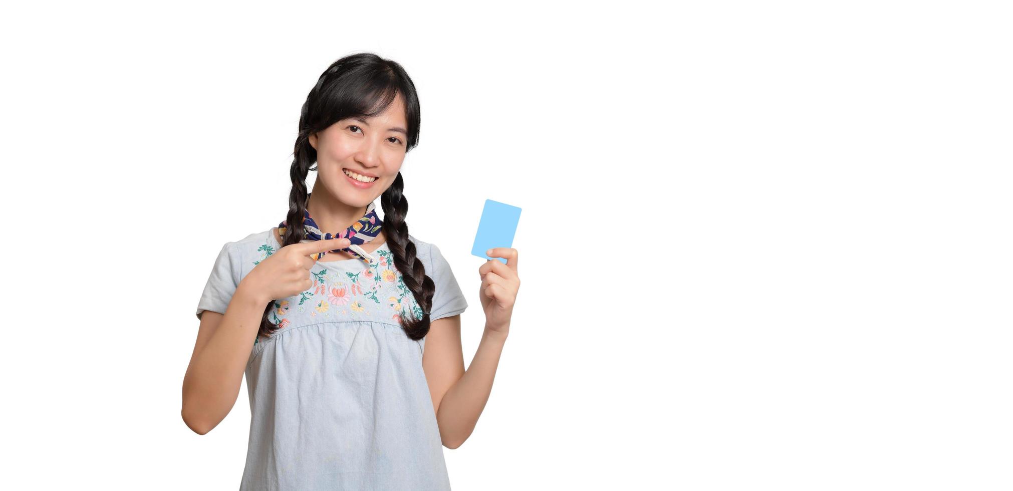 Portrait of beautiful happy young asian woman in denim dress holding credit card on white background photo