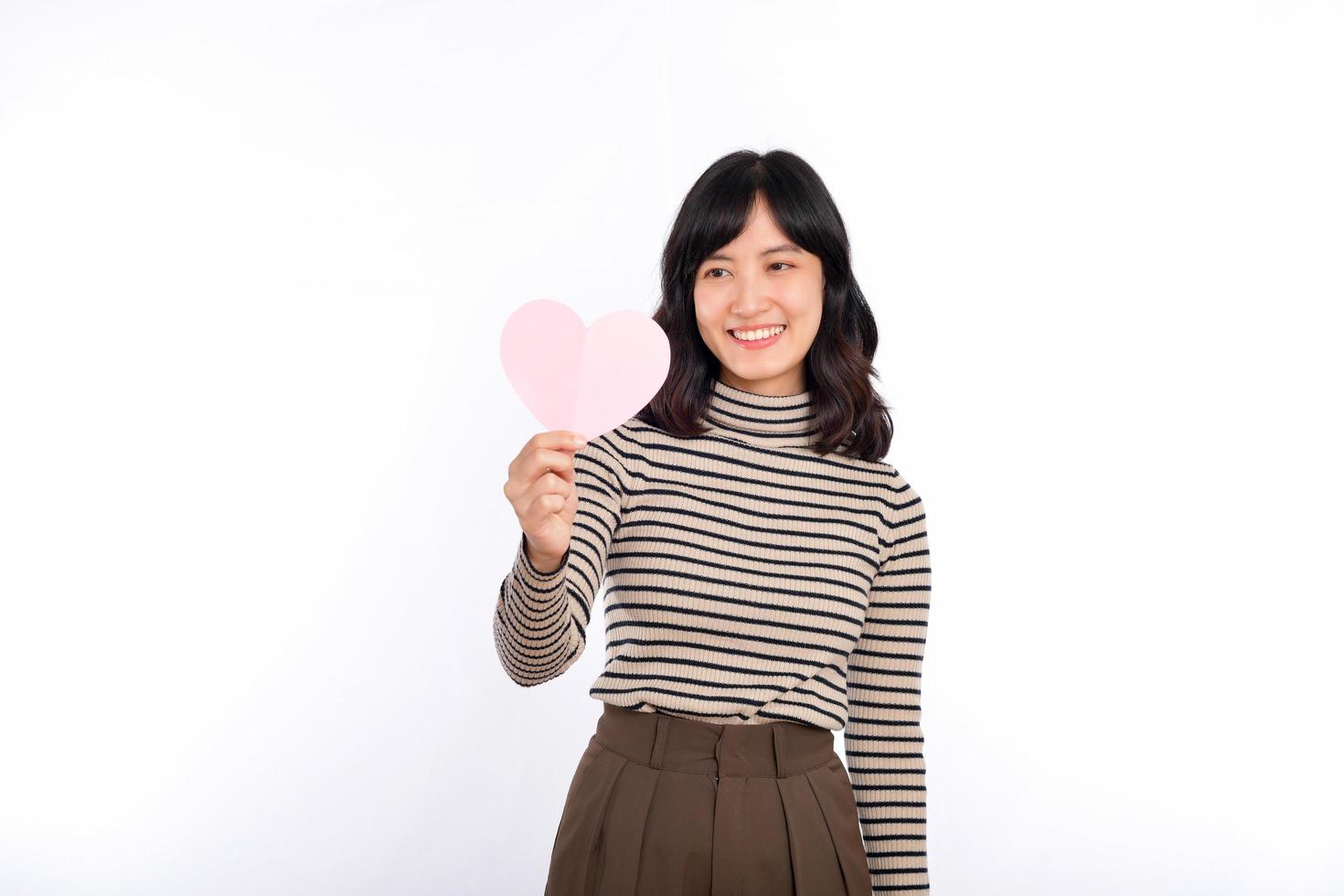 Beautiful young asian woman holding a paper heart while standing against white background. Beautiful young asian woman with paper heart. photo