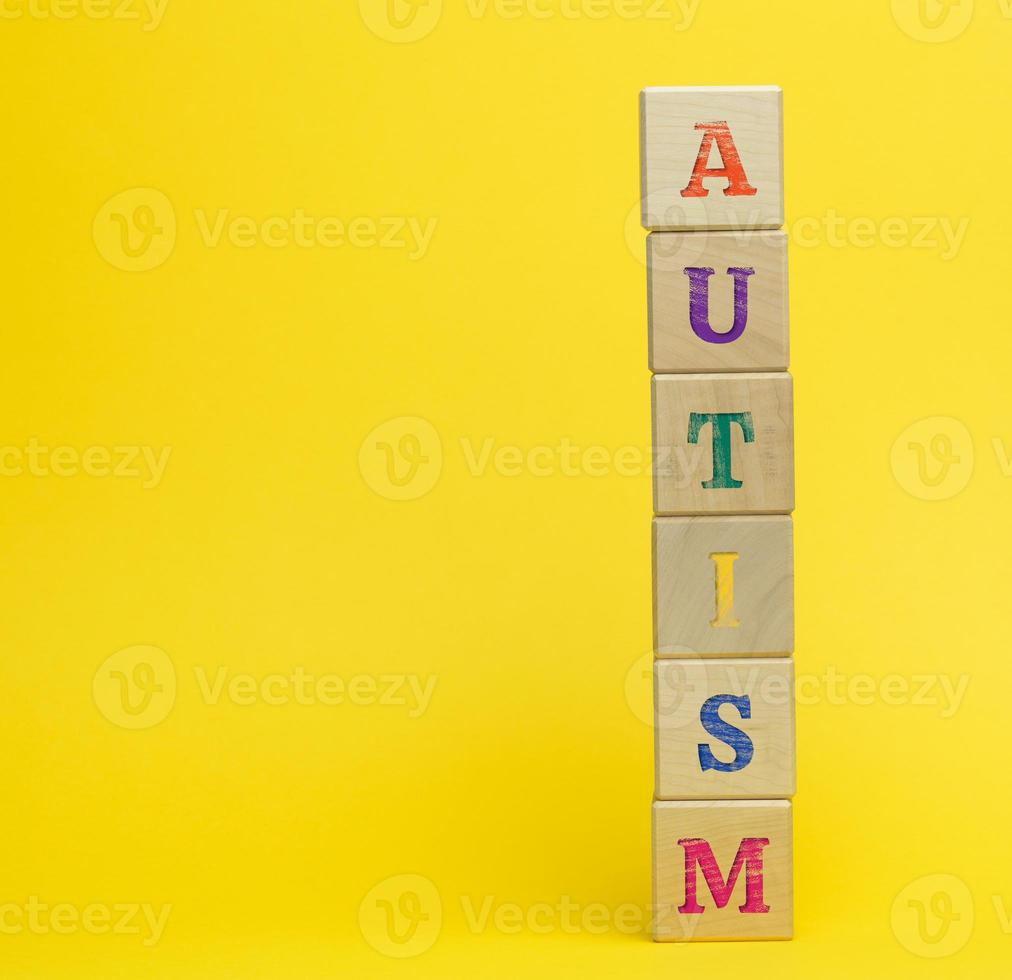 wooden cubes with the inscription autism on a yellow background. Concept of support and encouragement for children with developmental disorders of the brain photo