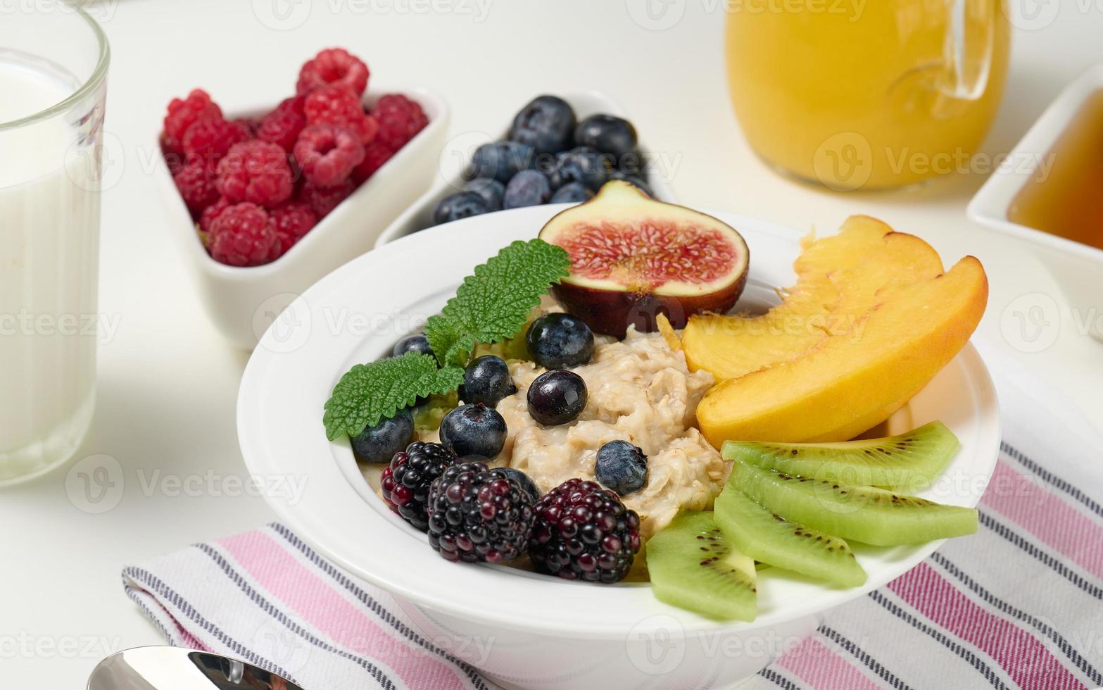 full plate with oatmeal and fruit, freshly squeezed juice in a transparent glass decanter. Healthy breakfast photo