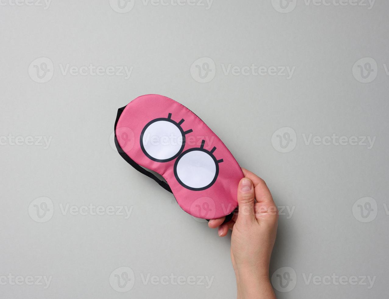 pink textile mask in a female hand on a gray background photo