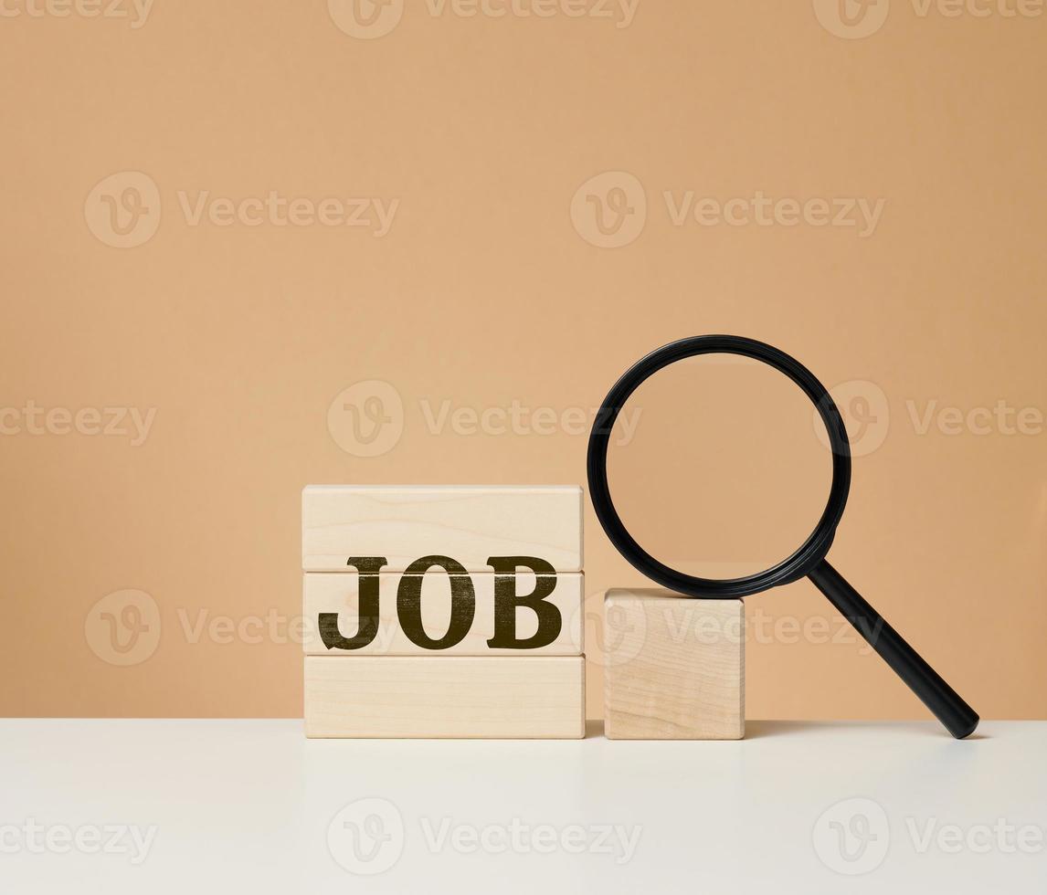 Wooden cubes with the inscription work and a black magnifier on a white table. Job search, unemployment photo