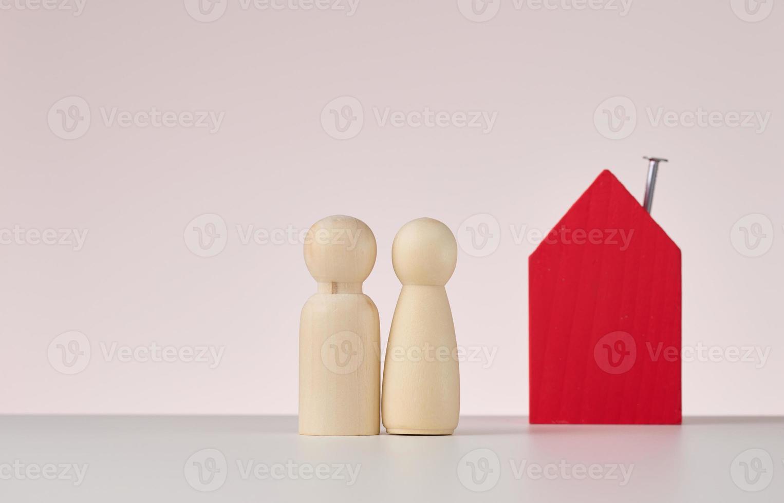 de madera cifras de hombres y un miniatura casa en un beige antecedentes. el concepto de comprando o de venta real bienes, hipoteca y propiedad seguro foto