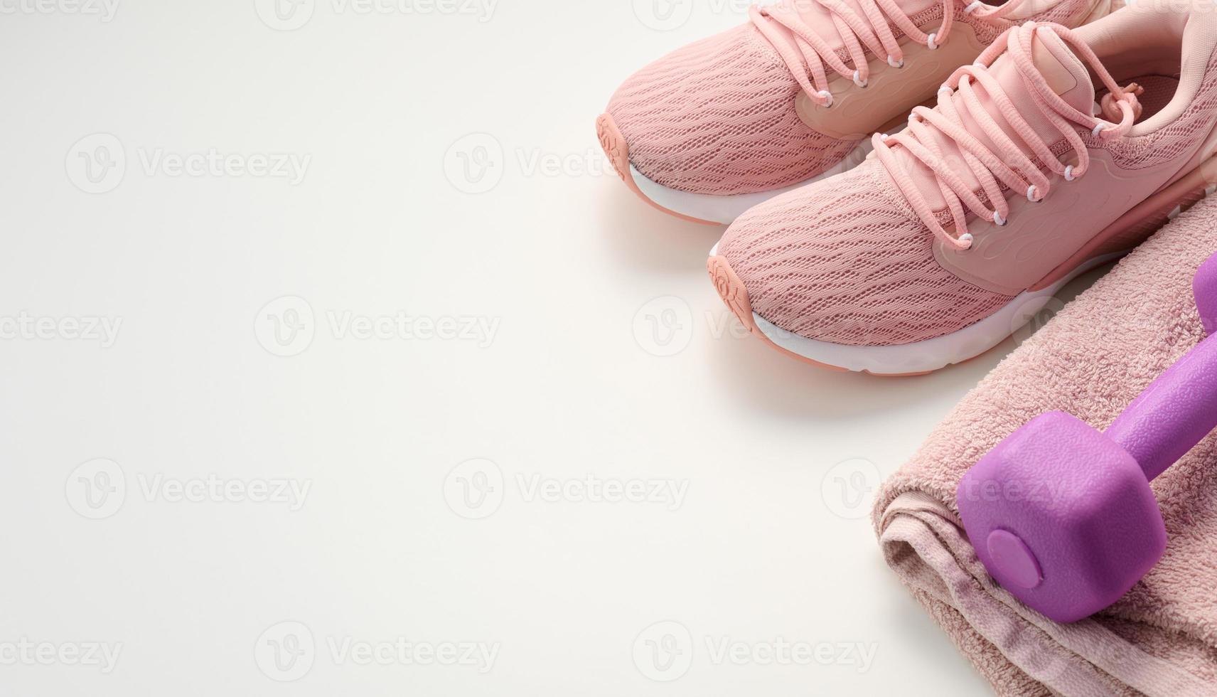pair of pink sneakers, a terry towel and a plastic dumbbell on a white background photo