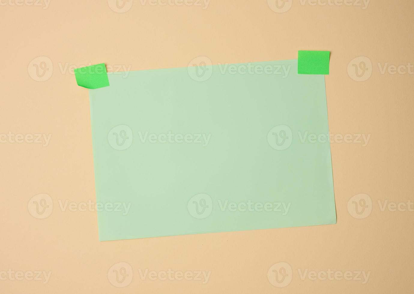 rectangular blank green sheet of paper glued with green sticky paper on light brown background photo