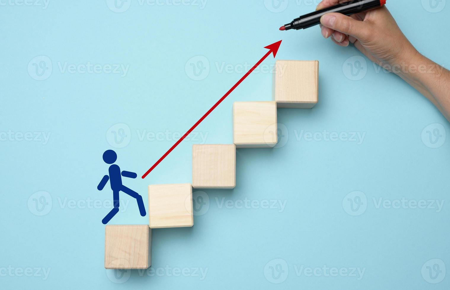 Wooden man and steps. A woman's hand drew an arrow with a red marker. photo