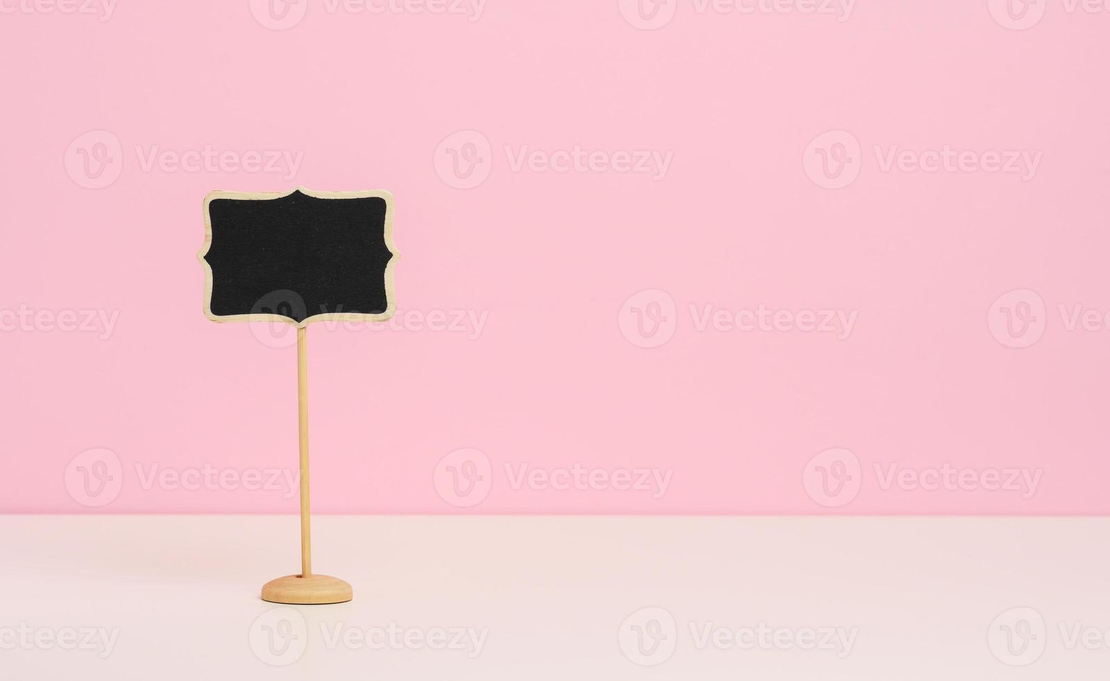 empty wooden pointer on a stick for writing text, pink background photo