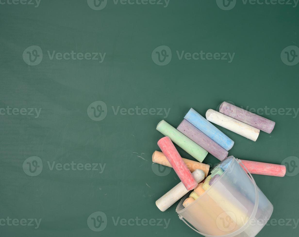 multicolored crayons on the background of green chalk school blackboard photo