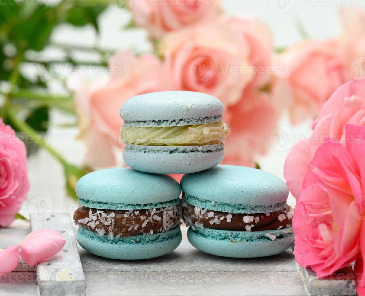 pila de macarons azules sobre una mesa blanca y capullos de rosa foto