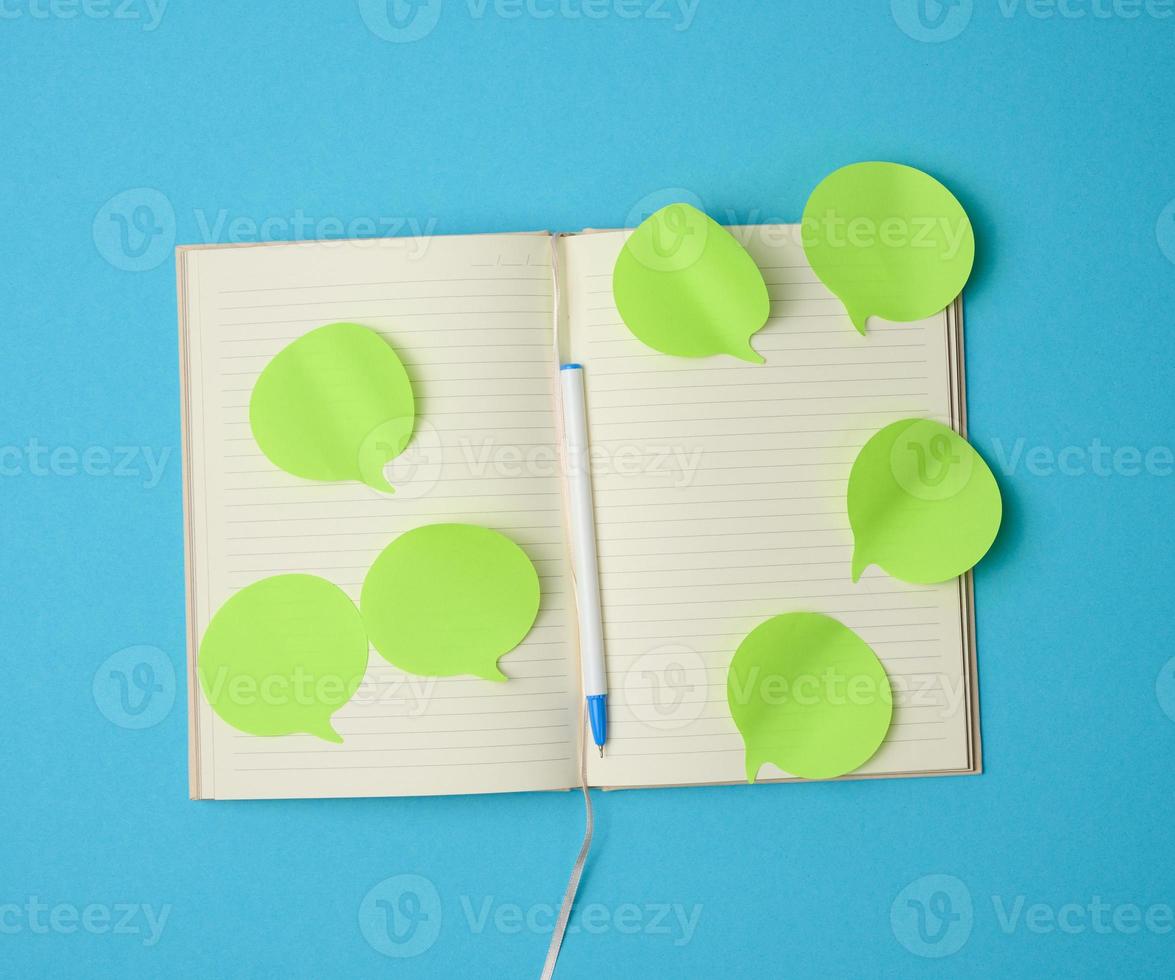 blank paper green stickers in the shape of a cloud glued to white sheets of a notebook, blue background photo