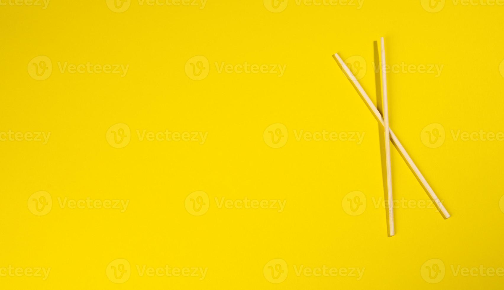 two wooden chopsticks on a yellow background photo