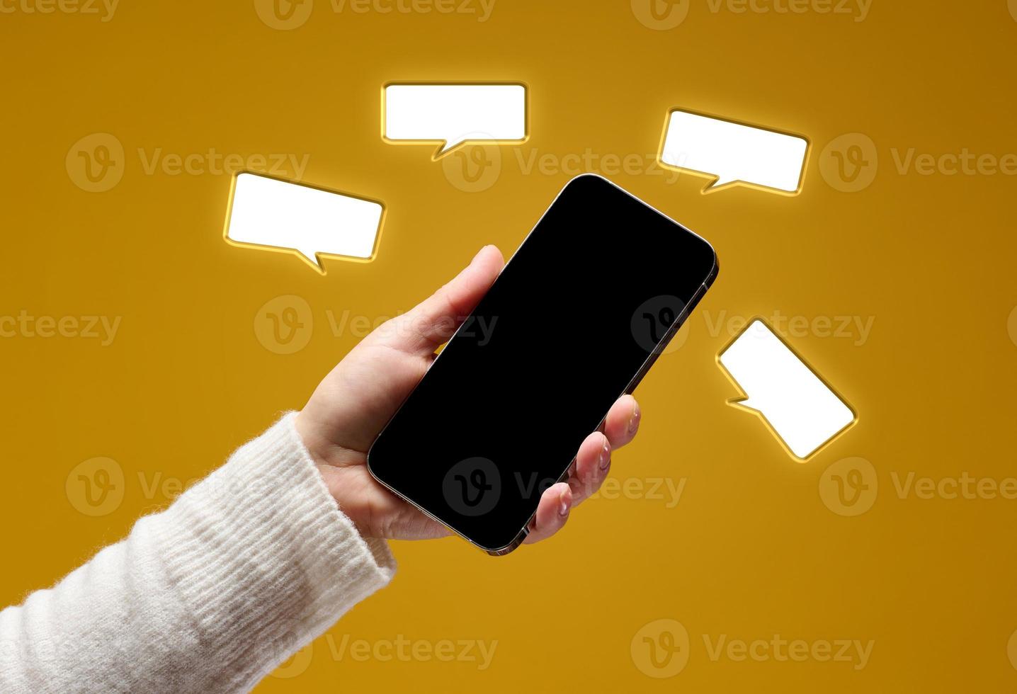 female hand holding smartphone with blank black screen on yellow background photo