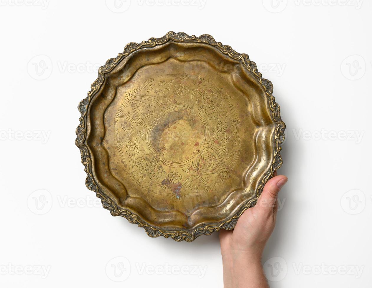 female hand holding empty copper round vintage plate on white background, fruit dish photo