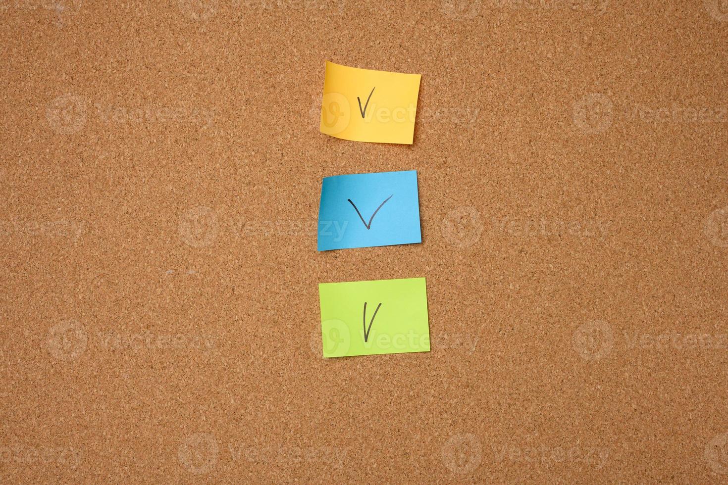 colorful paper stickers glued to brown cork board photo