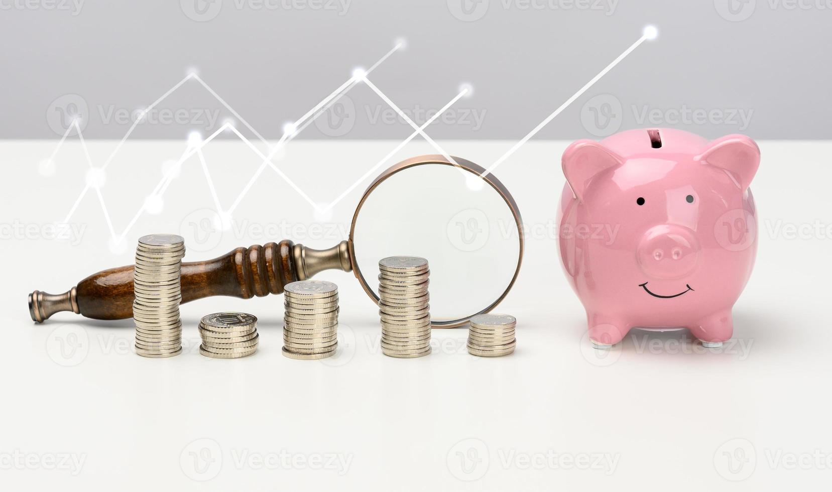 de madera lupa y rosado cerámico cerdito banco y un apilar de monedas en un blanco mesa. ahorros concepto, presupuesto planificación. ingresos crecimiento foto