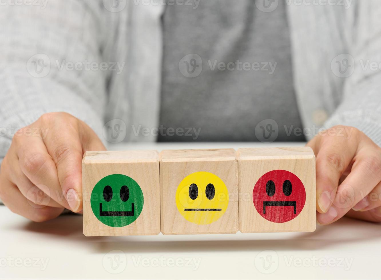 wooden blocks with different emotions from smile to sadness and a woman's hand. concept for assessing the quality of a product or service, emotional state, user reviews photo