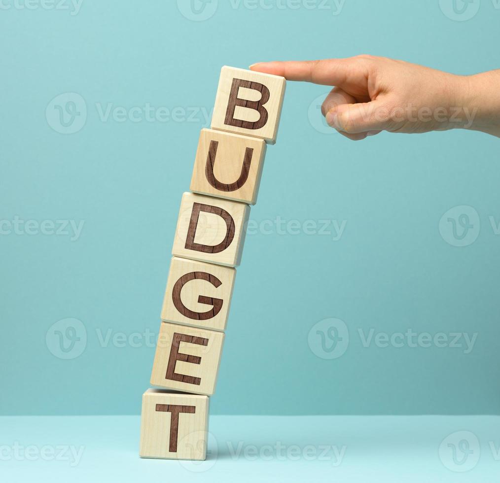 wooden blocks with the inscription budget is held by a female hand on a blue background. Business concept of planning, saving and investment photo