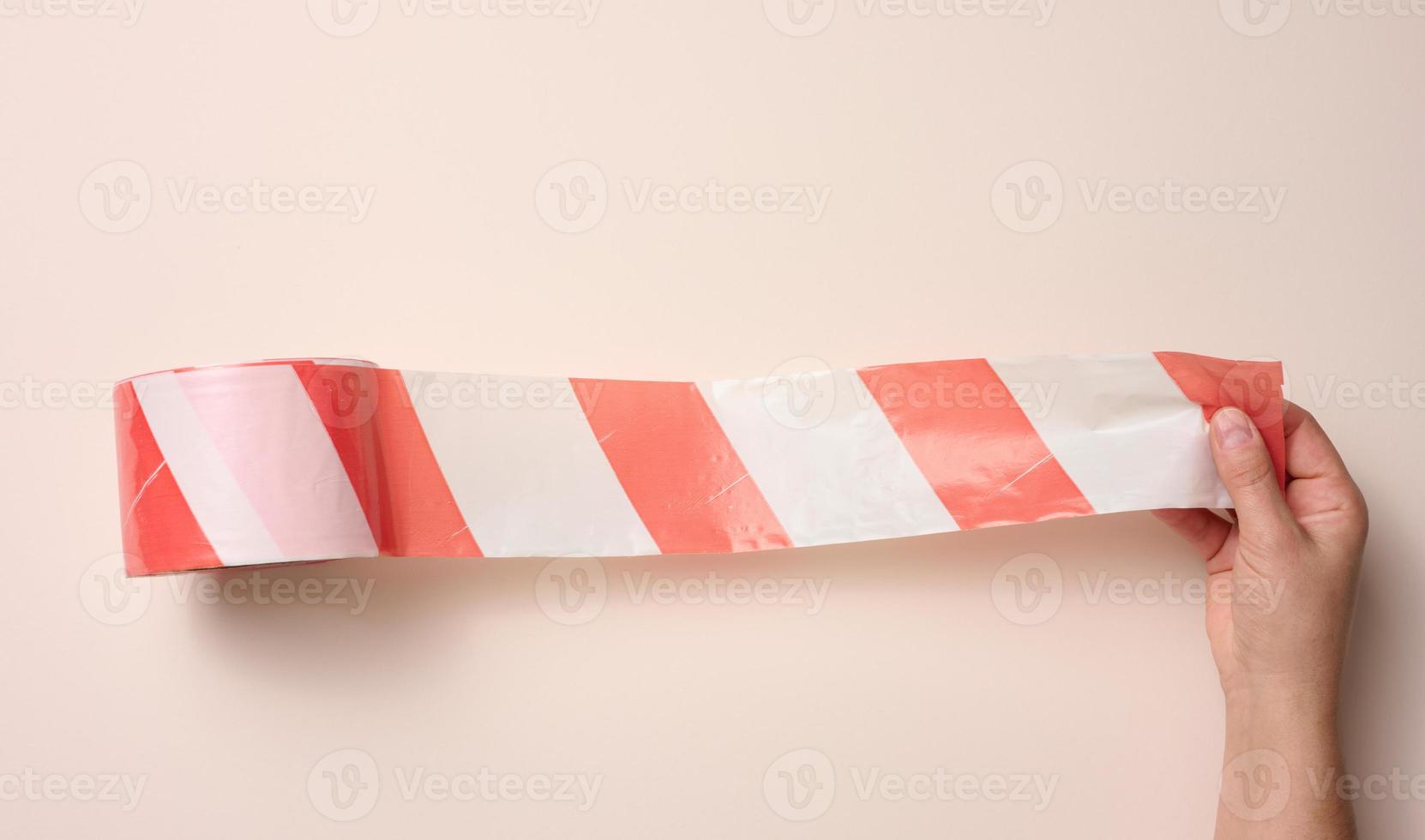 female hand holding a roll of protective tape on a beige background photo