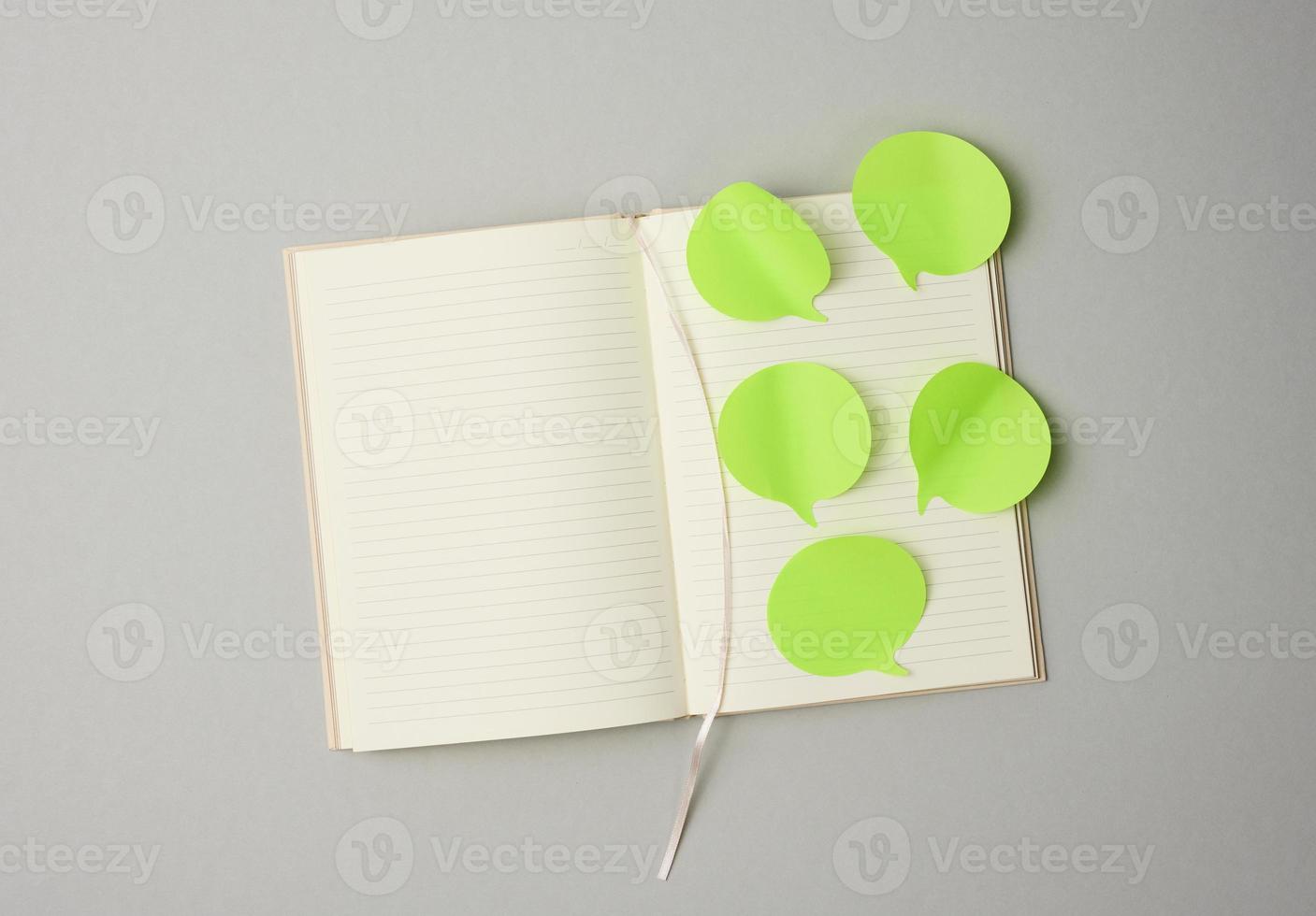 blank paper green stickers in the shape of a cloud glued to white sheets of a notebook, gray background photo