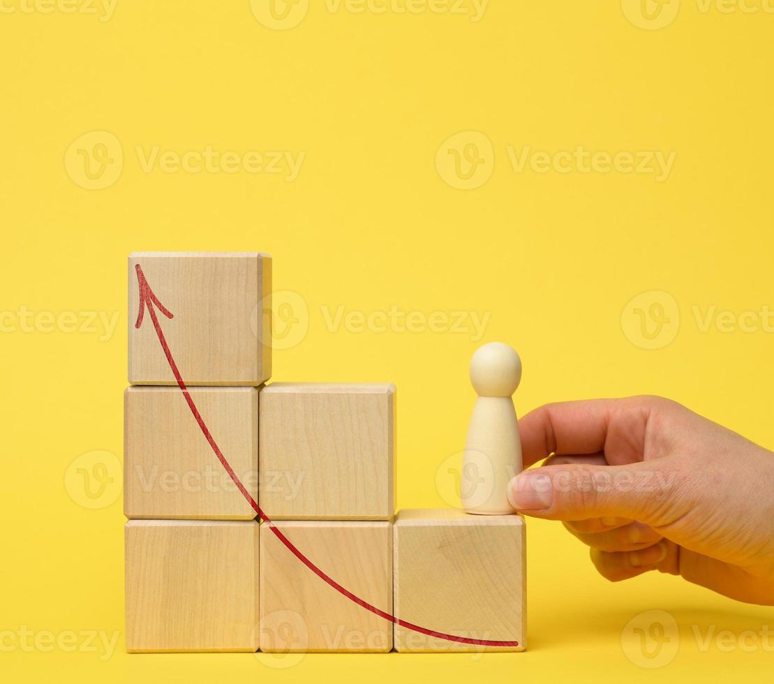 female hand holds a wooden figurine on a ladder of cubes on a jelly background. Career growth concept photo