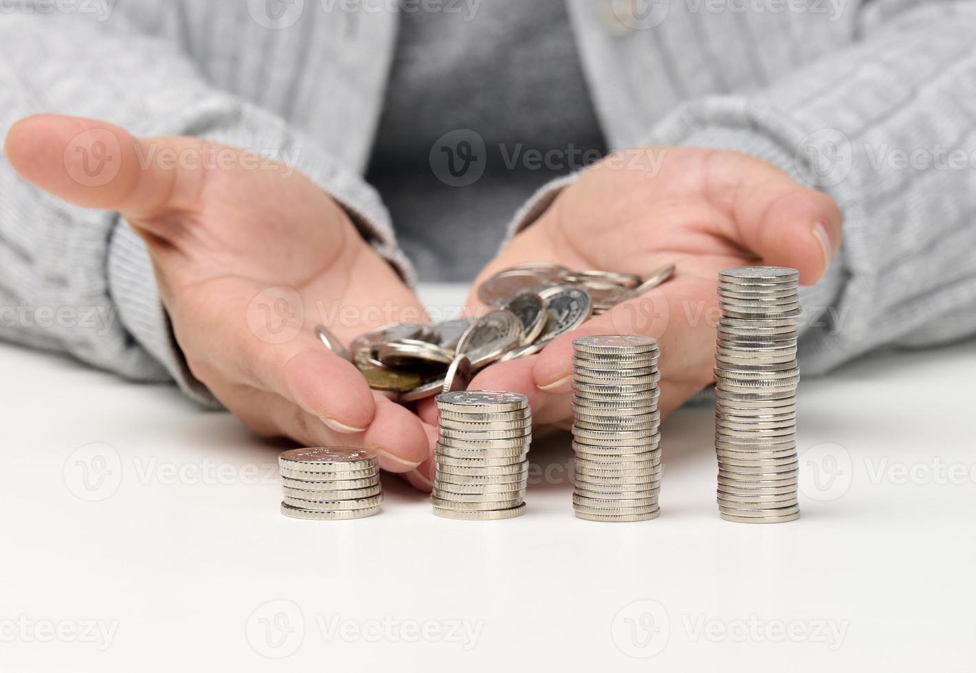 stack of white coins and female hands are holding a pile of coins. Poverty, budget planning. Subsidy and low salary photo