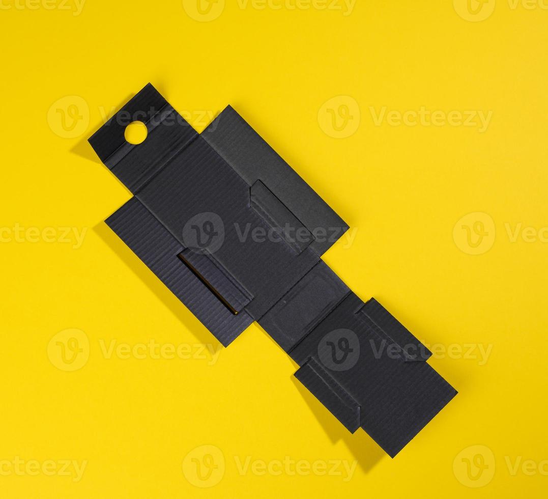 collapsible inner protective black box made of corrugated cardboard for packages with breakable goods on a yellow background photo