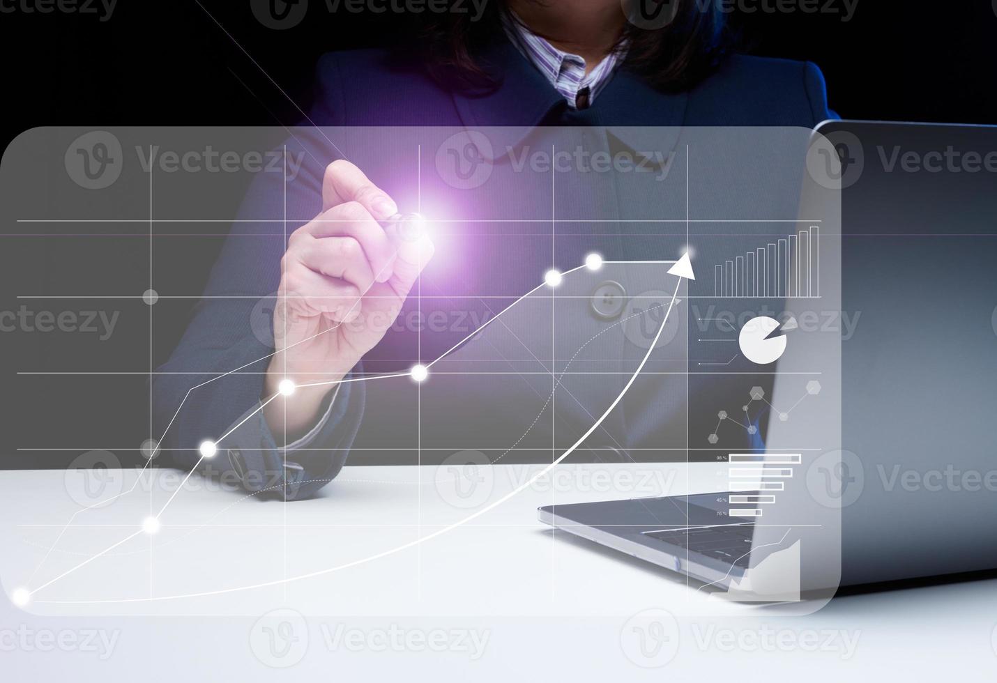 un mujer se sienta a un ordenador portátil en frente de un holográfico gráfico con creciente indicadores. negocio desarrollo, alto financiero actuación, éxito. foto