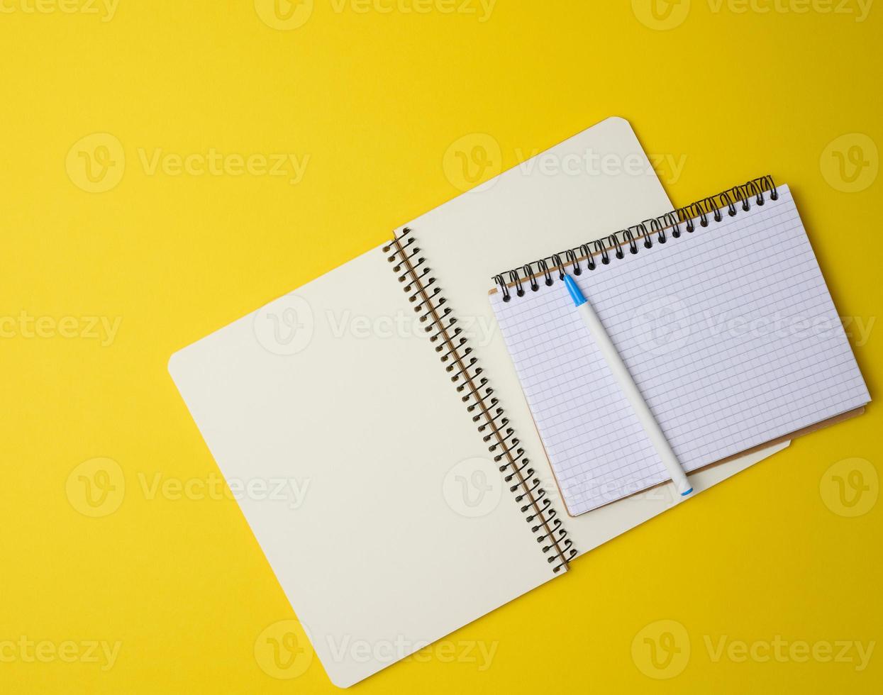open notebook in a cage with white blank sheet and on a yellow background, top view photo