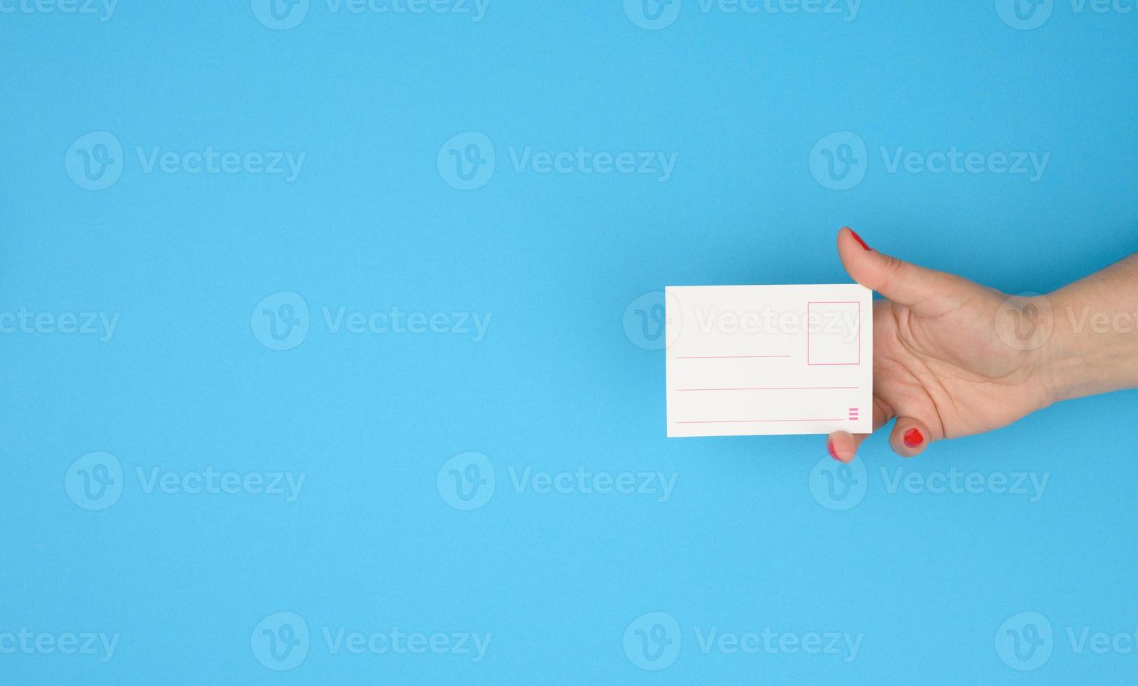 female hand holding paper blank badge insert on blue background photo
