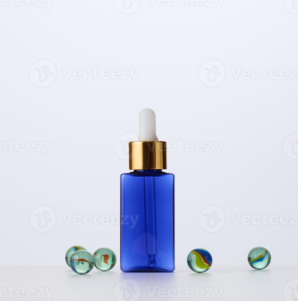 blue glass bottle with pipette for cosmetics, oils and serum. Advertising and product promotion photo