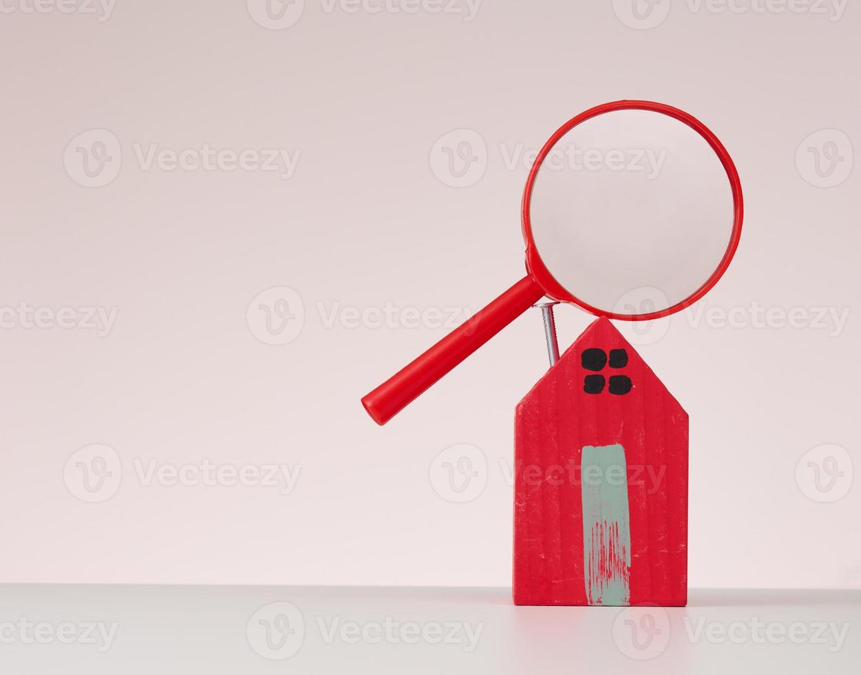 magnifier and wooden house on a beige background. Real estate rental, purchase and sale concept. Realtor services photo