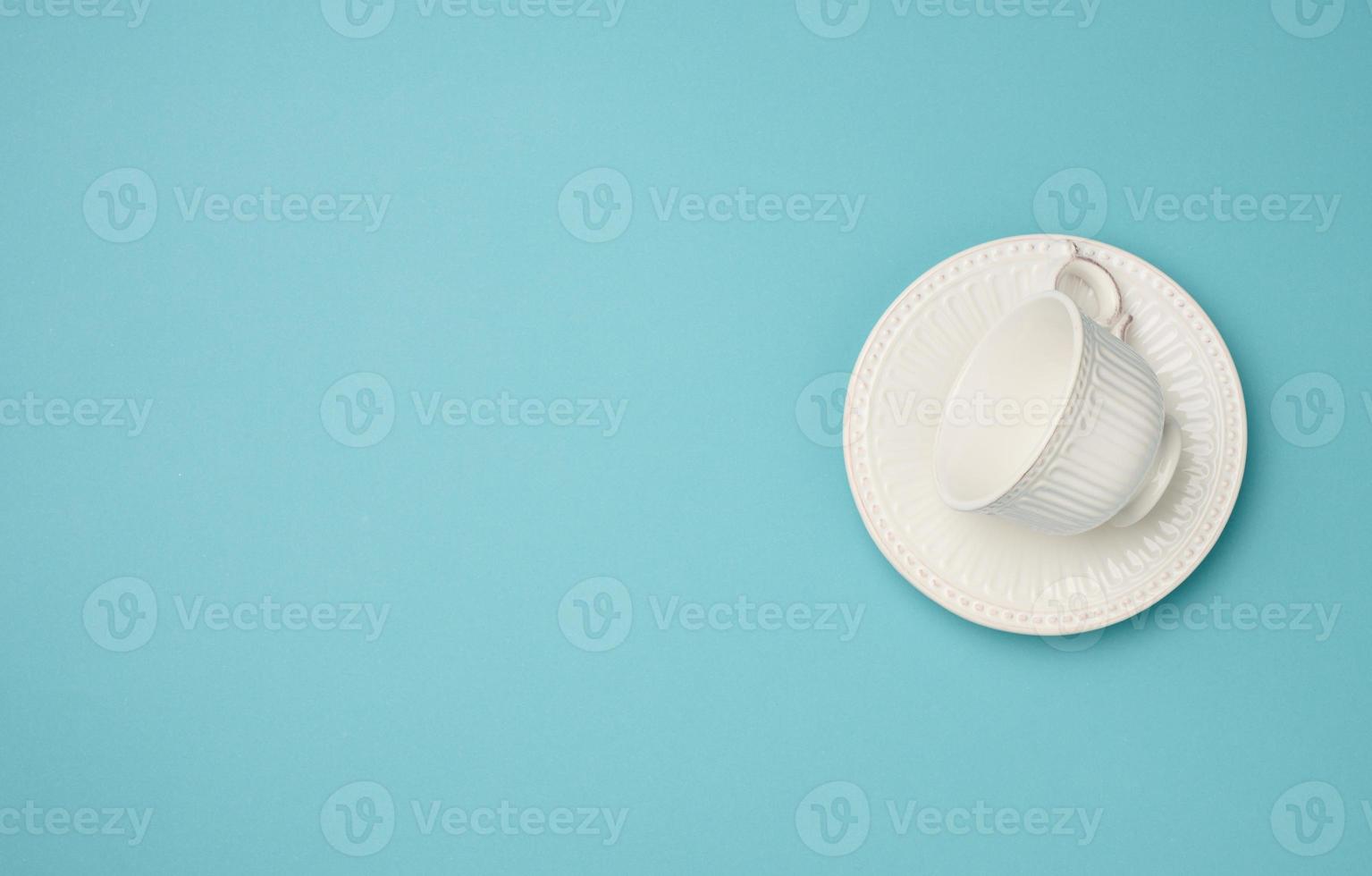 empty white ceramic cup and saucer on blue background, top view photo