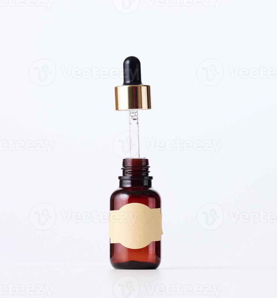 brown glass bottle with a pipette and a brown paper empty label on a white background. Container for cosmetics, oils, serums. Advertising and product promotion photo