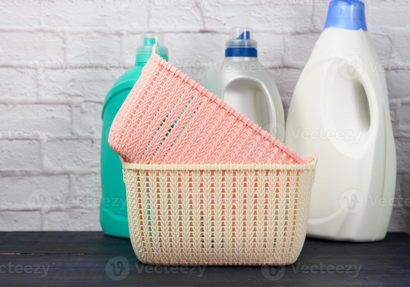 bottles with liquid detergent and plastic empty laundry baskets on a wooden blue table photo