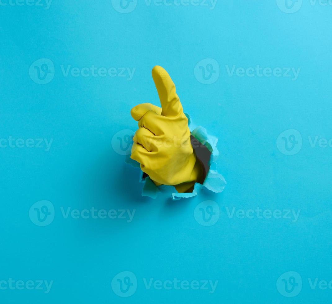 hand in a green latex glove points a finger on a blue background. Place for inscription of discounts, offer or announcement. photo
