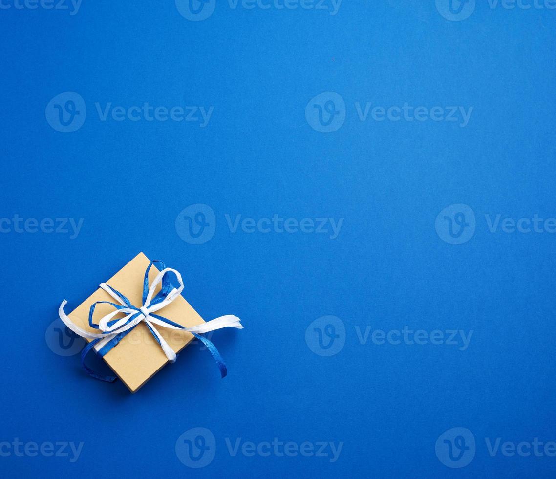 brown cardboard gift square box, bows on a blue background photo