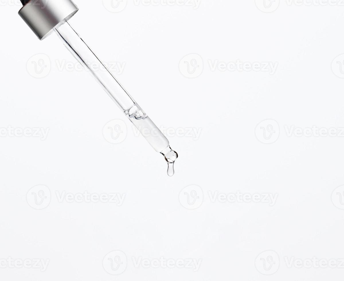 glass pipette with dripping transparent liquid on a white background. Acid, serum photo
