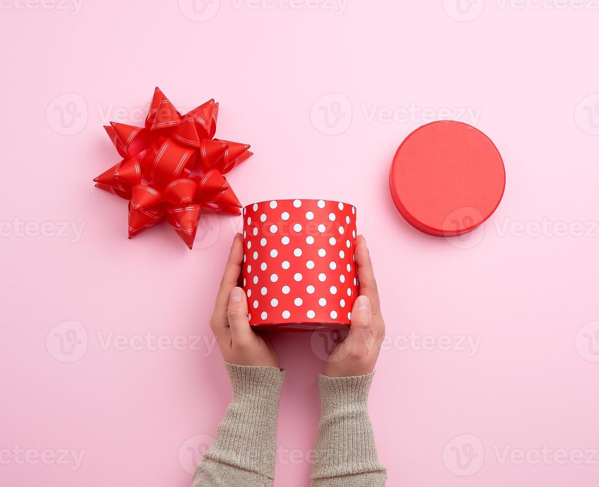 two female hands are holding a beautiful red open box with white polka dots photo