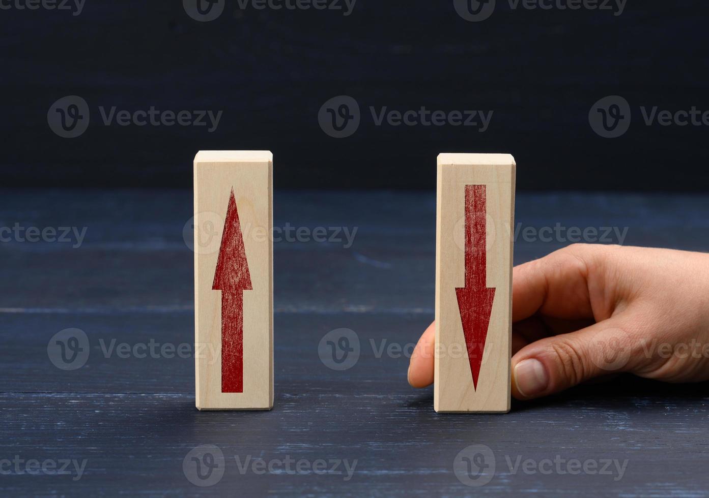 female hand holds a wooden block with an upward arrow and down arrow photo