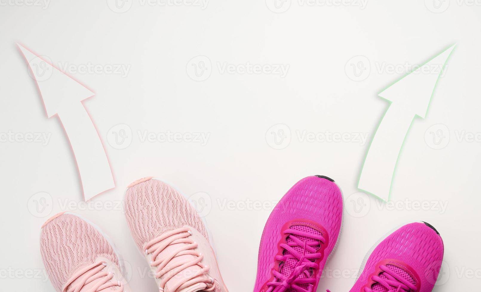 two pairs of pink textile sneakers are directed in opposite directions. Quarrel and difference of opinion concept, different life paths and interests photo