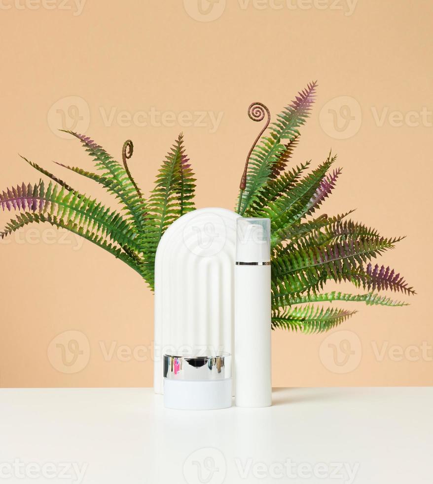 white plastic bottle and jar for cosmetics on a white table photo