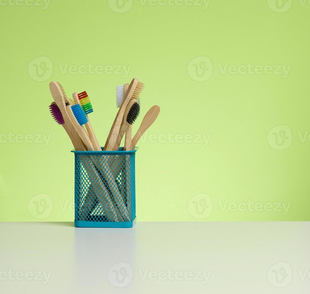 wooden toothbrushes in a plastic cup on a white table photo