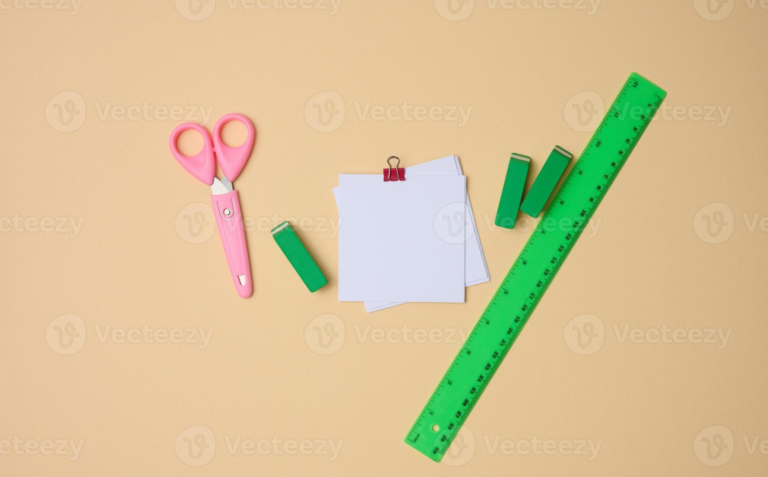 set of stationery objects ruler, blank white paper sheets ina beige background. View from abovegreen photo