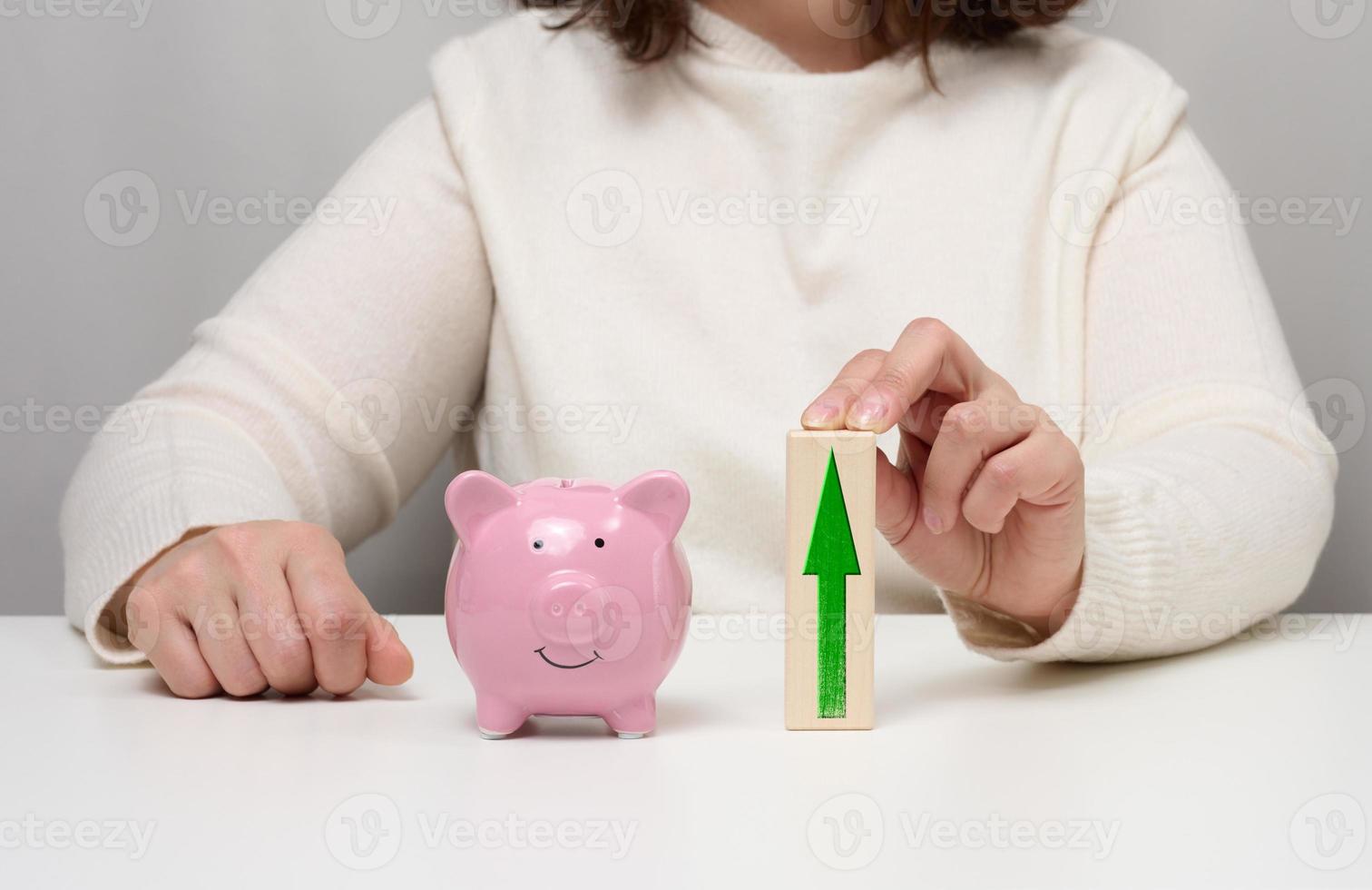 Pink ceramic piggy bank and wooden blocks with up arrow. Concept of increasing interest on a deposit in a bank photo